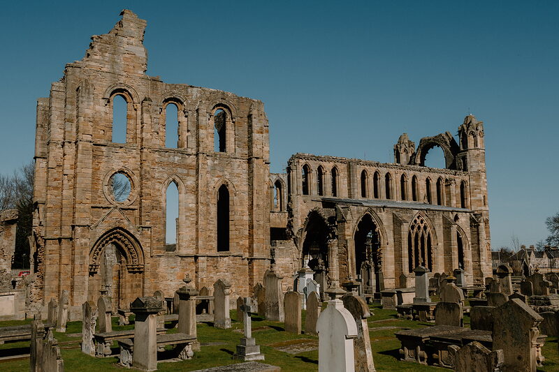 The twin towers and roofless nave of Elgin Cathedral stand among rows of gravestones.