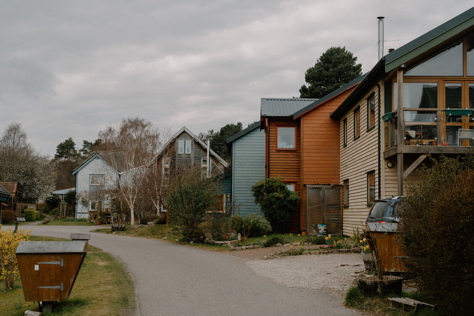 A row of eclectic self-built timber houses lines a street at the Findhorn Foundation ecovillage, Moray.