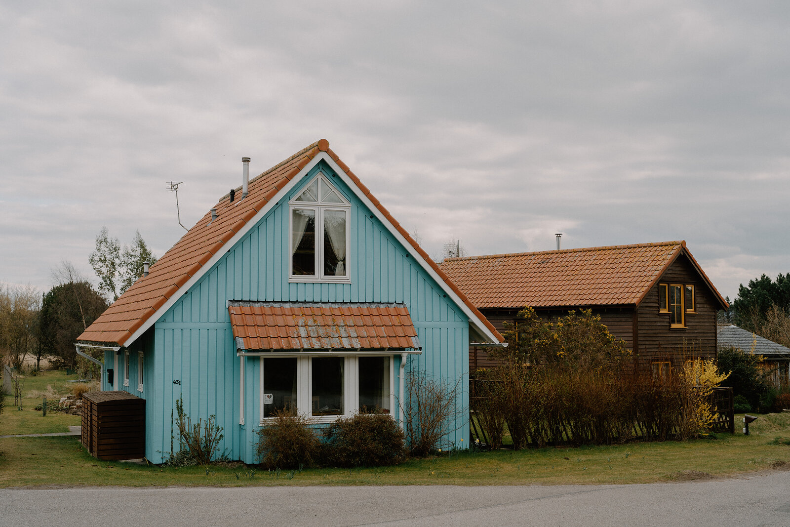 A pale blue timber house with an orange-tiled porch roof stands at the Findhorn Foundation ecovillage, Moray.