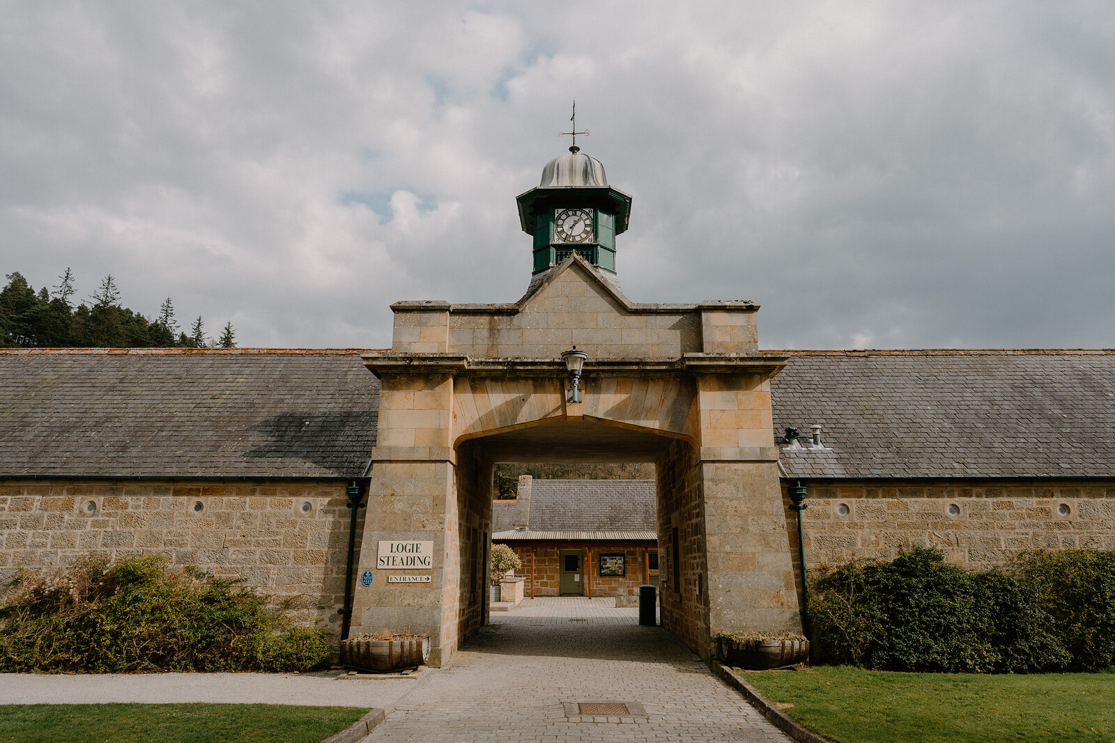 An archway beneath Logie Steading's green-domed clock tower carries the estate's name on a stone plaque.