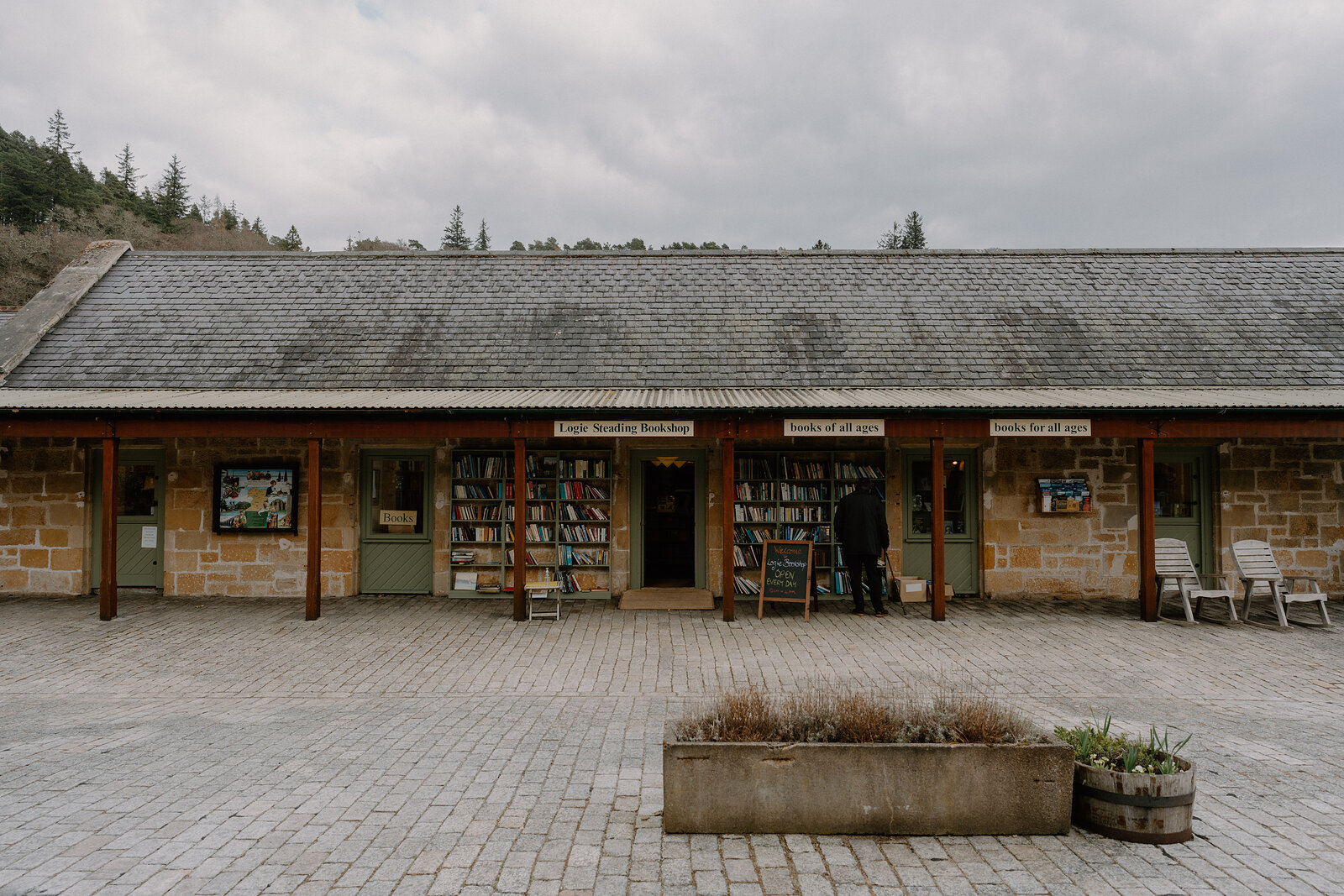 Logie Steading's bookshop spills shelves onto its covered walkway, a wicker chair set outside the door.