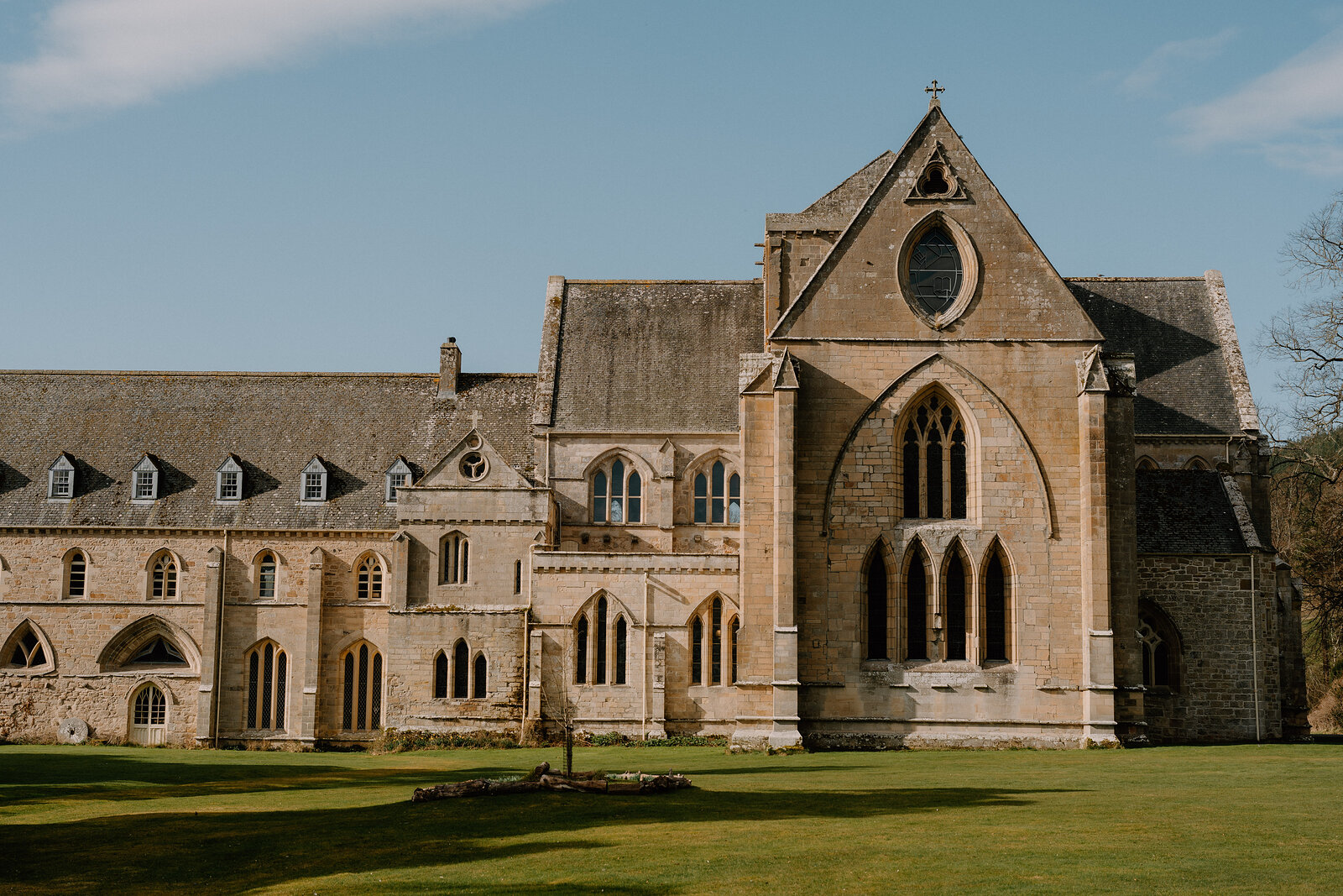Pluscarden Abbey's gothic sandstone facade rises above a wide lawn in Moray.