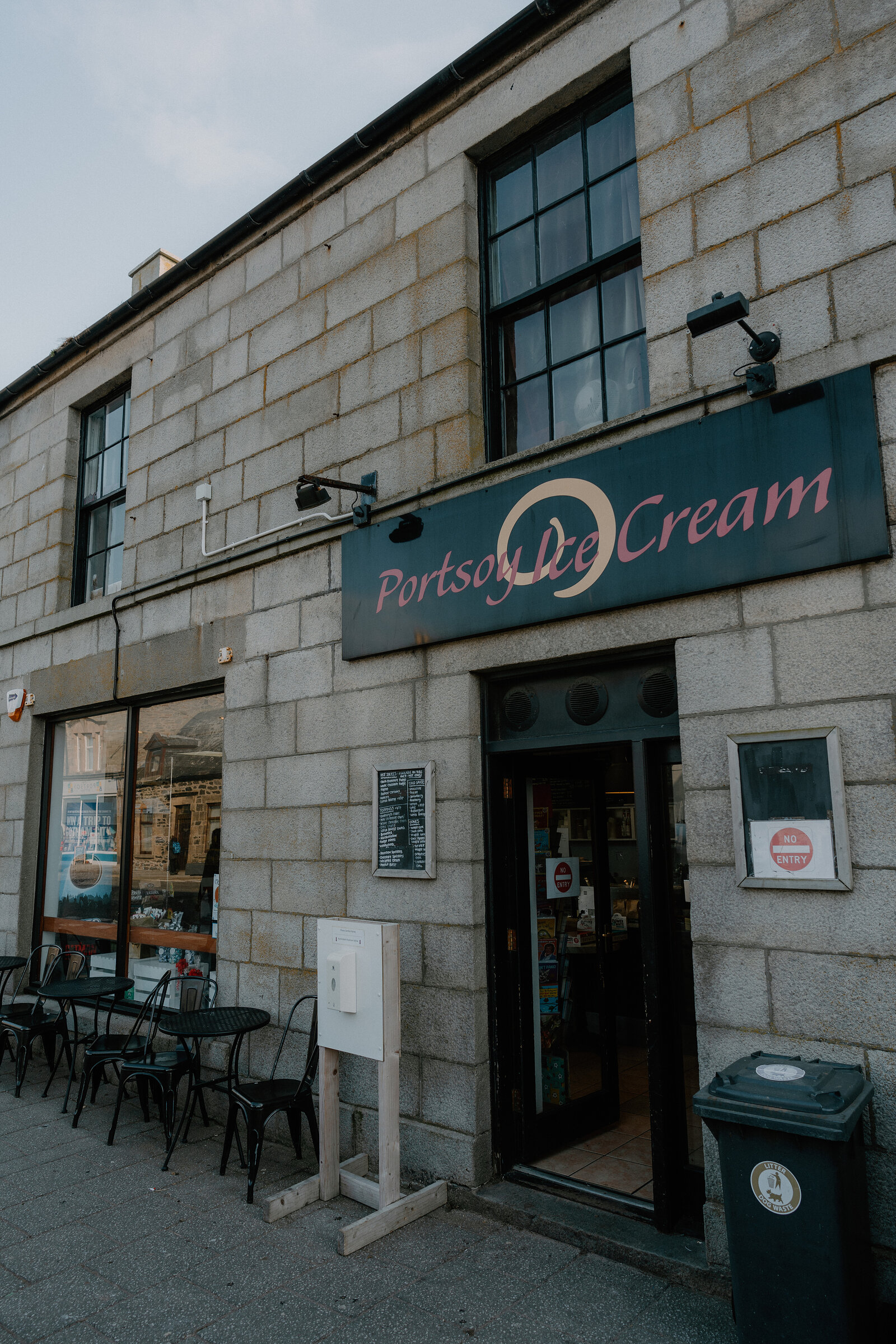 Portsoy Ice Cream's granite shopfront holds pavement tables and a chalkboard menu by its open door.