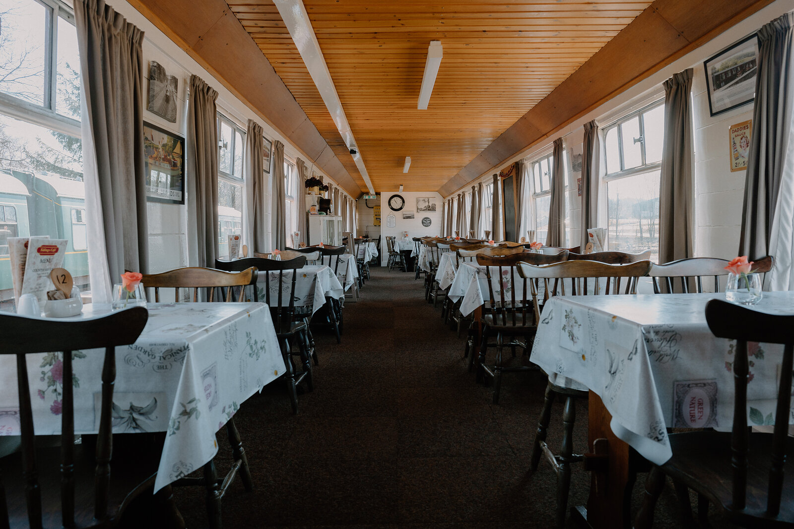 Rows of cloth-covered tables line Sidings Café's carriage beneath curtained windows.
