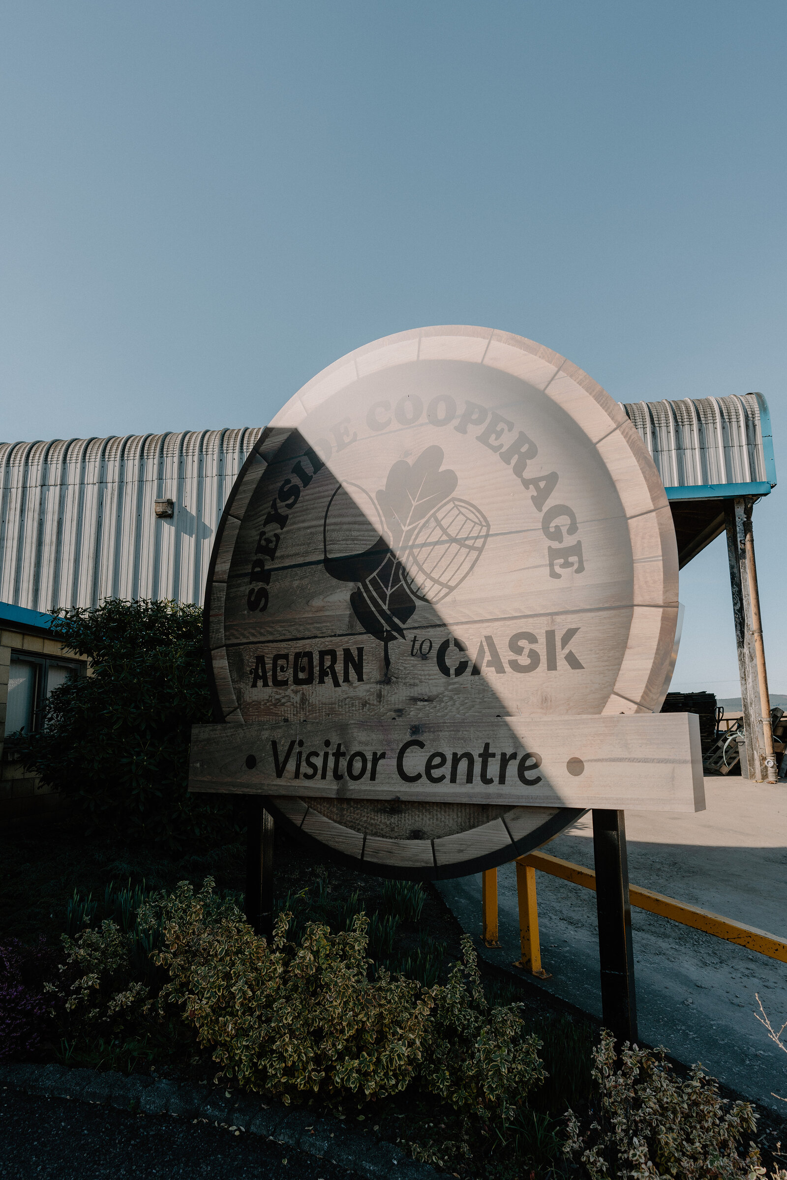 A giant barrel-shaped sign reads 'Speyside Cooperage, Acorn to Cask, Visitor Centre' beside its steel-roofed building.
