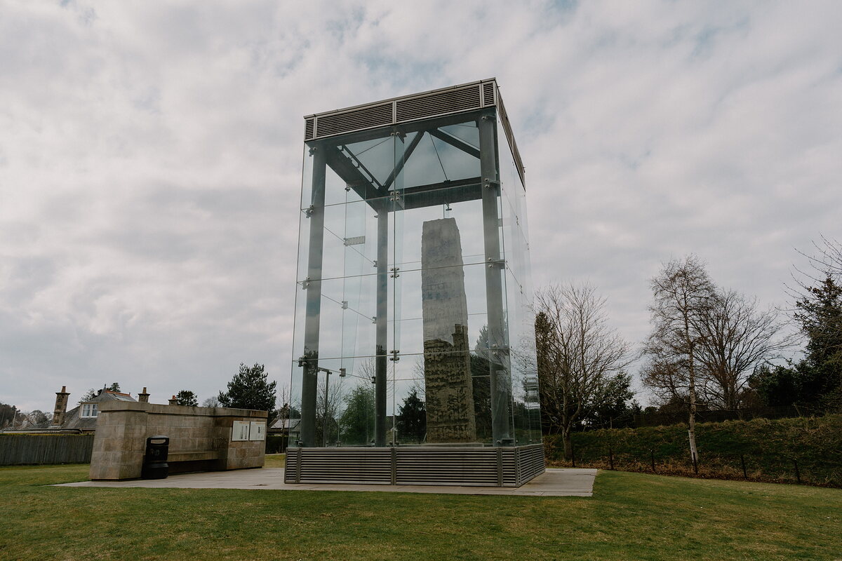 Sueno's Stone stands encased in glass on a lawn near Forres, its carved surface catching the light.