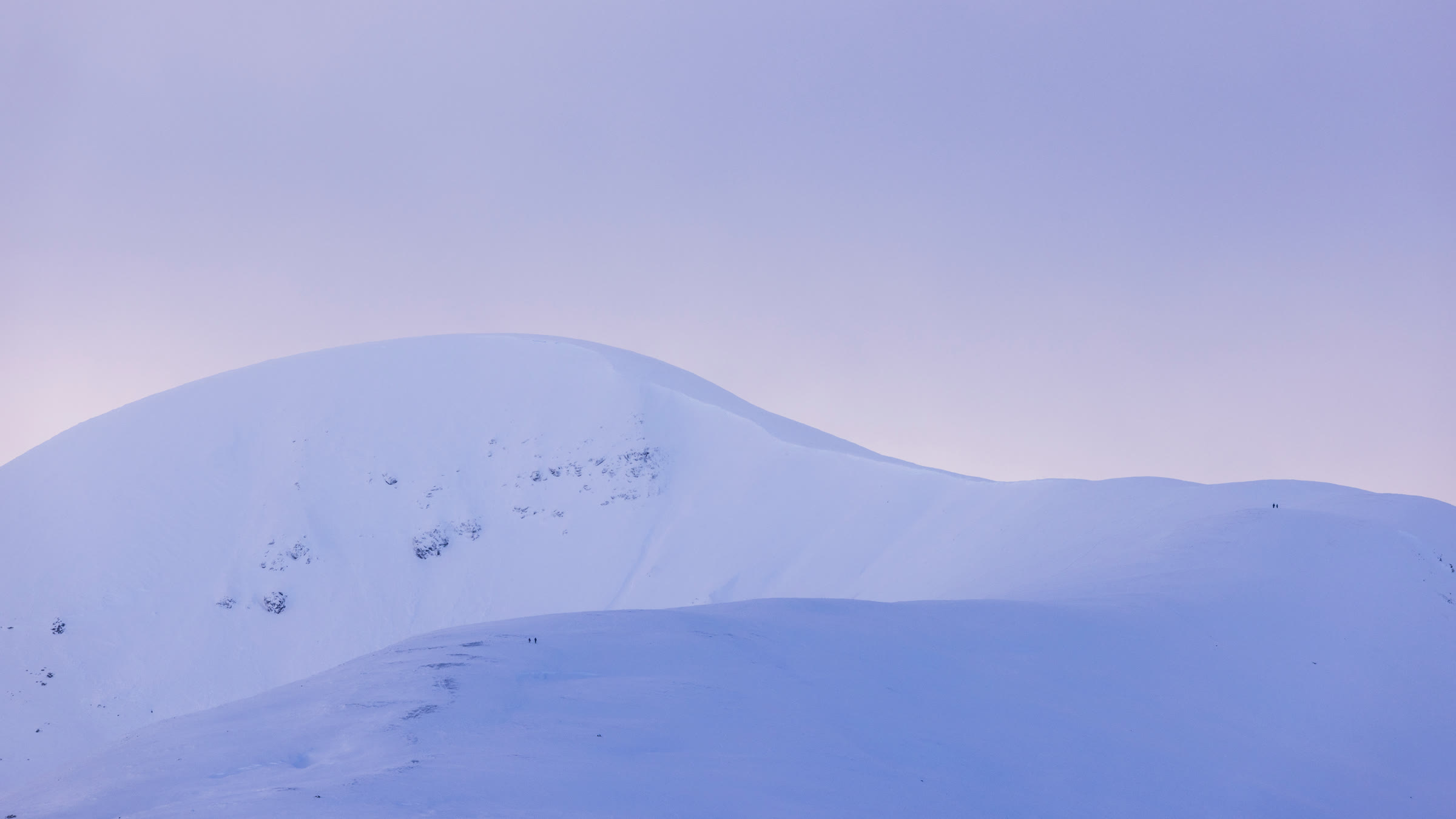 The broad snow dome of A' Mharconaich in pale pink evening light.