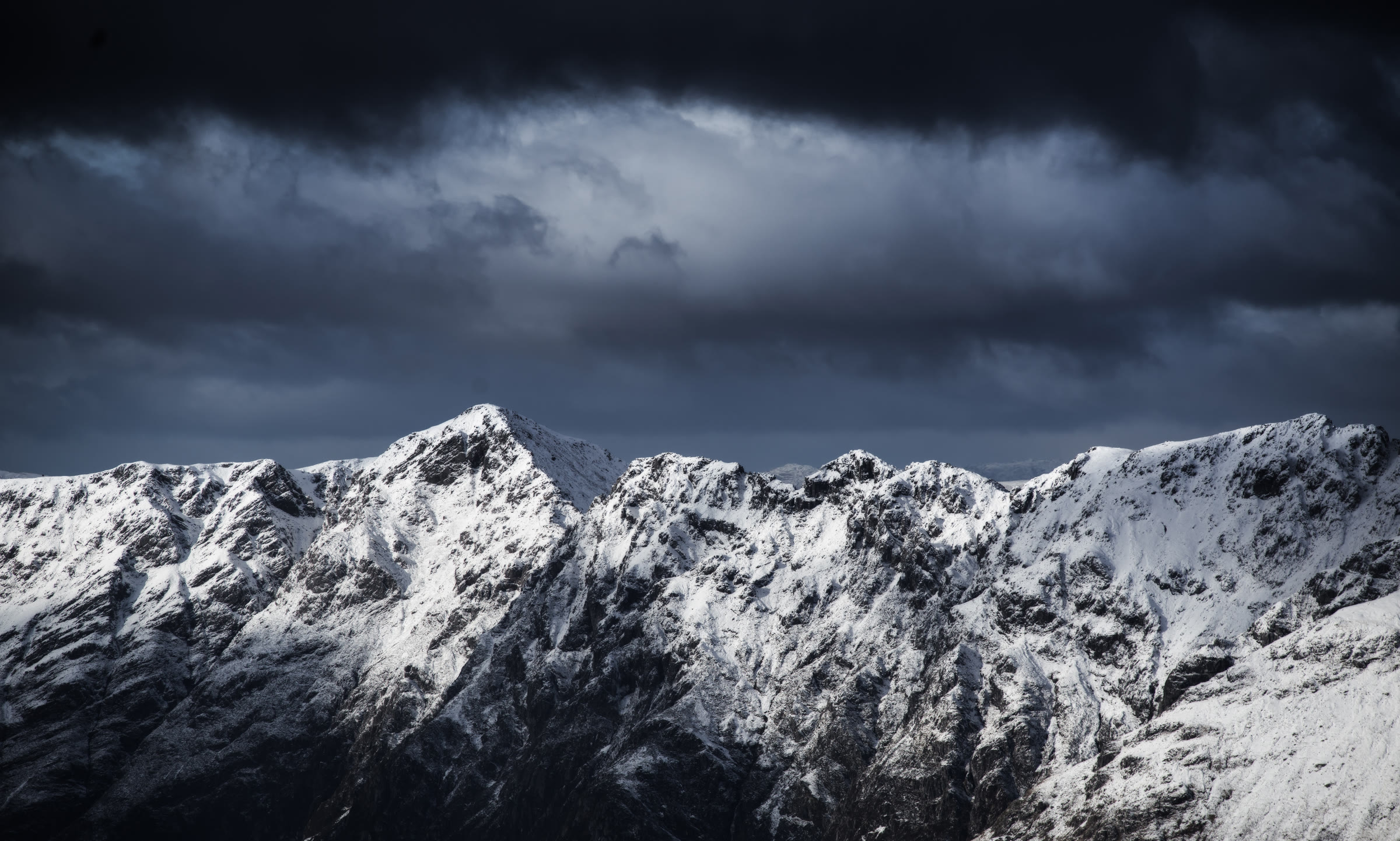 The Aonach Eagach under snow, dark cloud over the ridge.