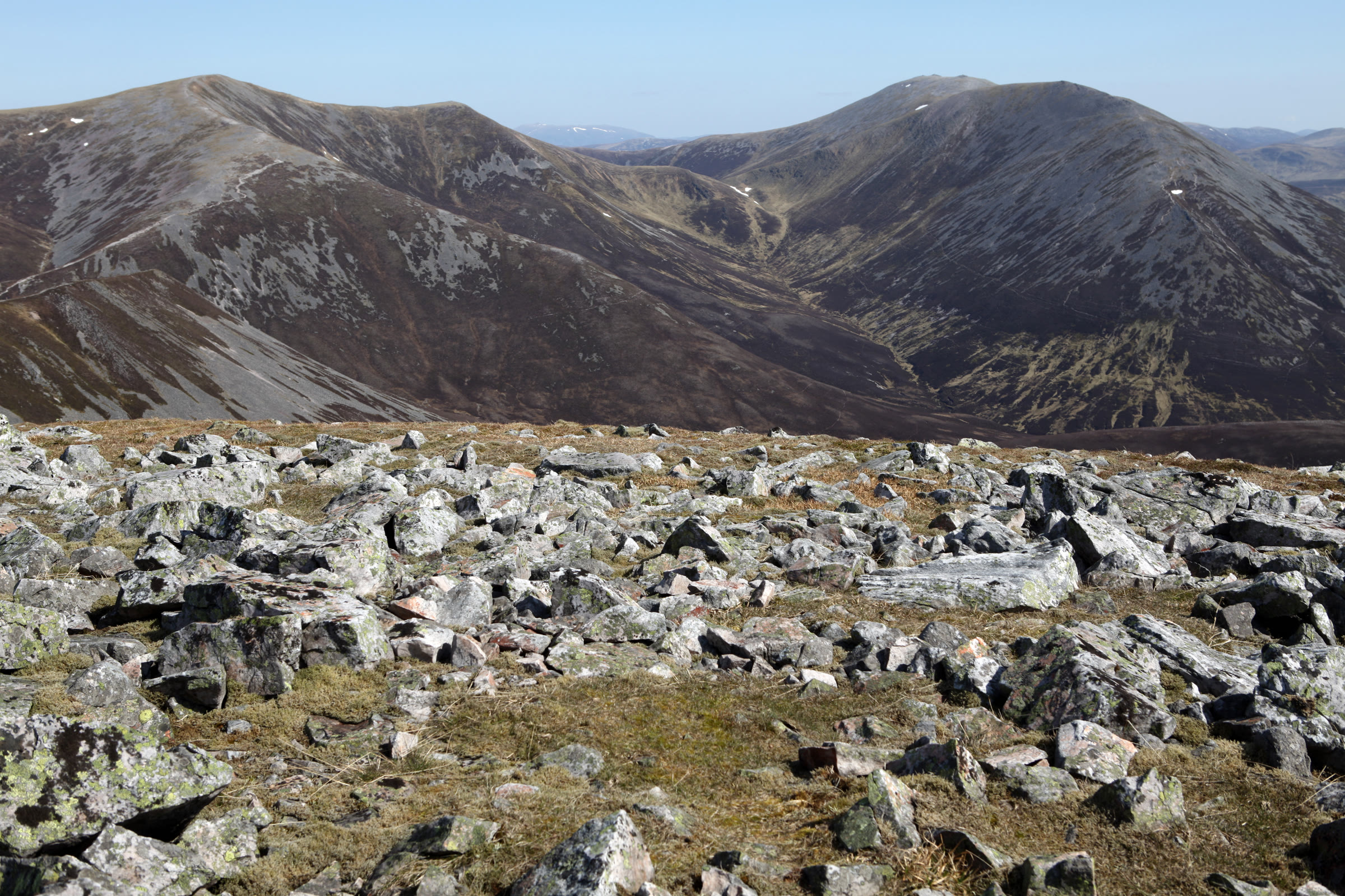 Two of the Beinn a' Ghlò hills across a stony summit, scree streaking their heather slopes.
