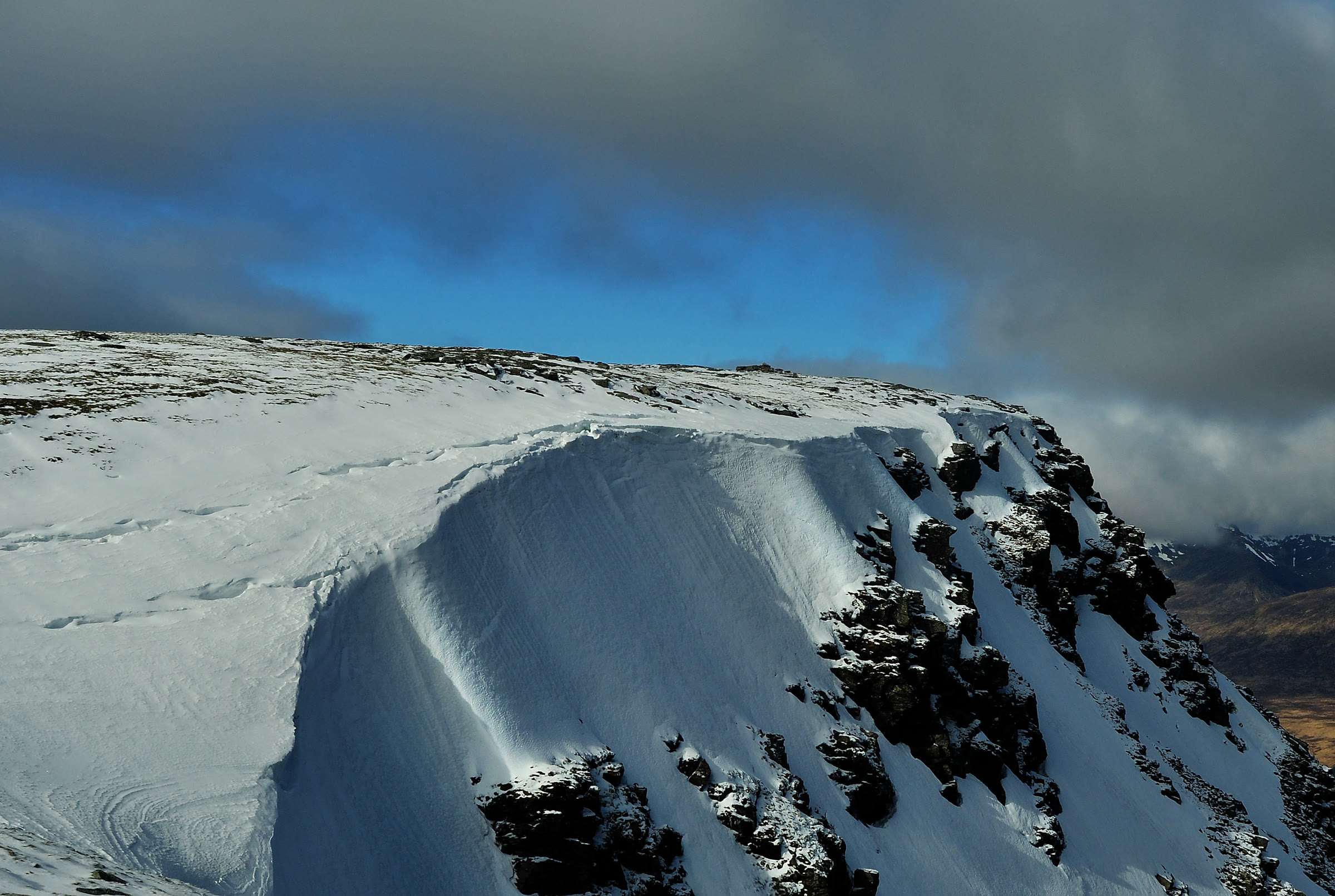 A corniced edge of snow above dark crags on Beinn an Dòthaidh.