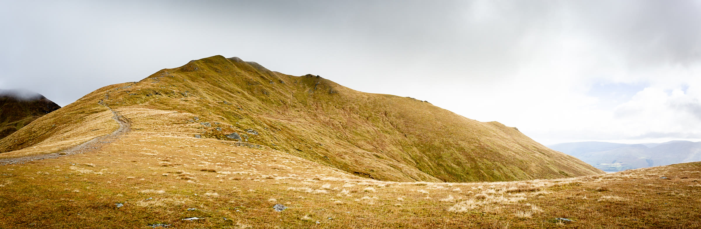 Beinn Ghlas in low golden light, the path curving across its grassy shoulder.
