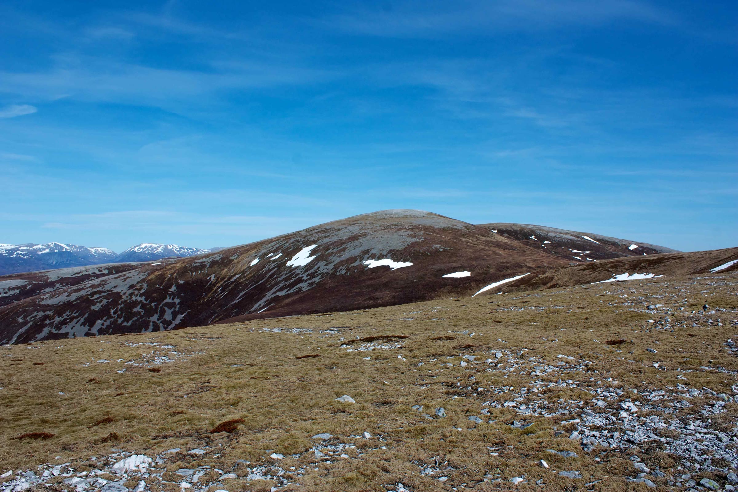 The rounded top of Beinn Iutharn Mhòr with the last snow patches, under a deep blue sky.