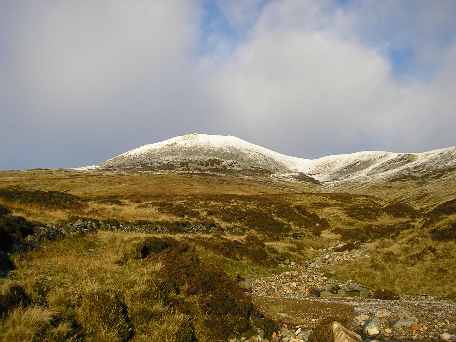 Càrn a' Chlamain white with snow, seen from the north across tawny moorland and a burn.
