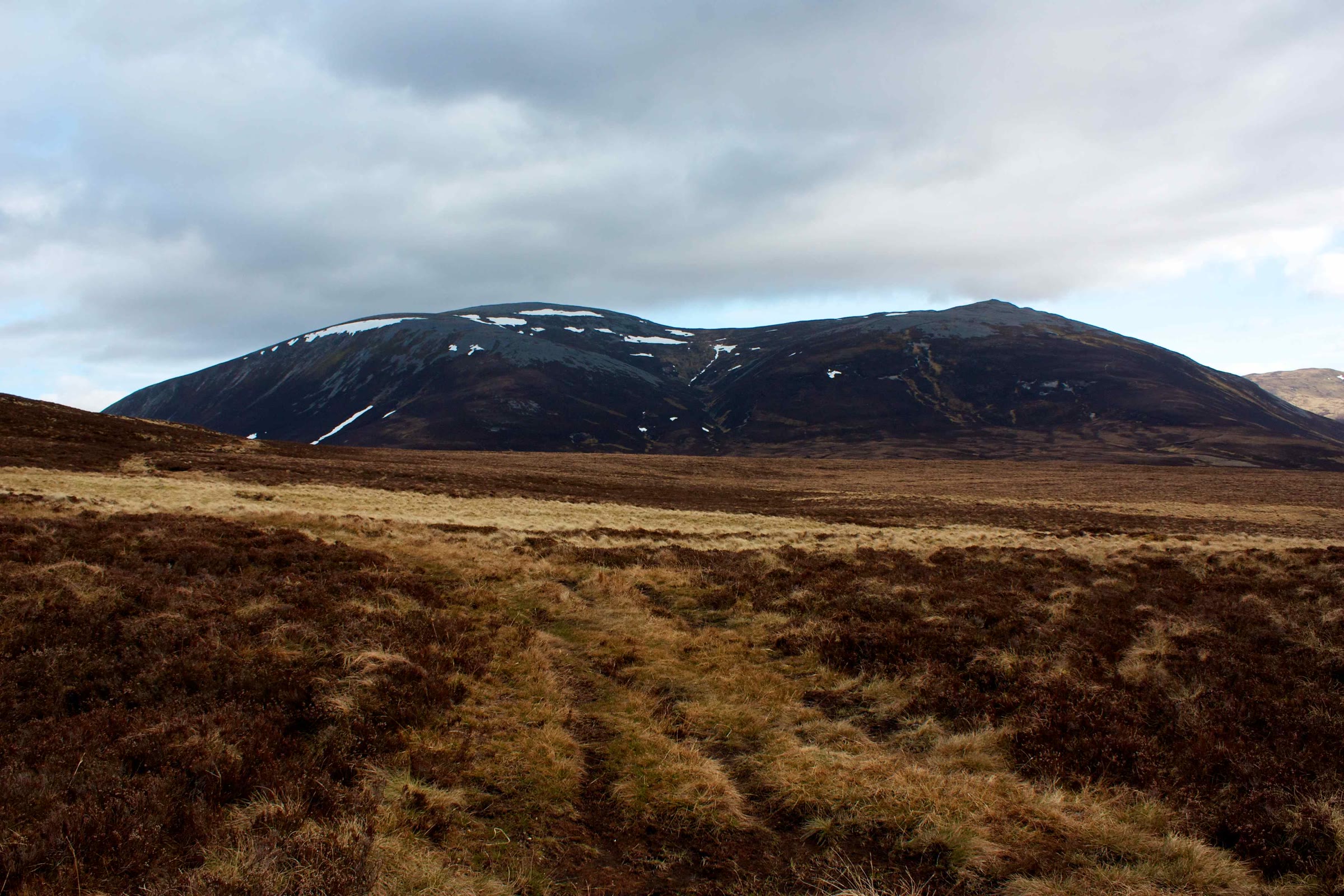 Càrn an Rìgh across tawny moorland under a cloudy sky.
