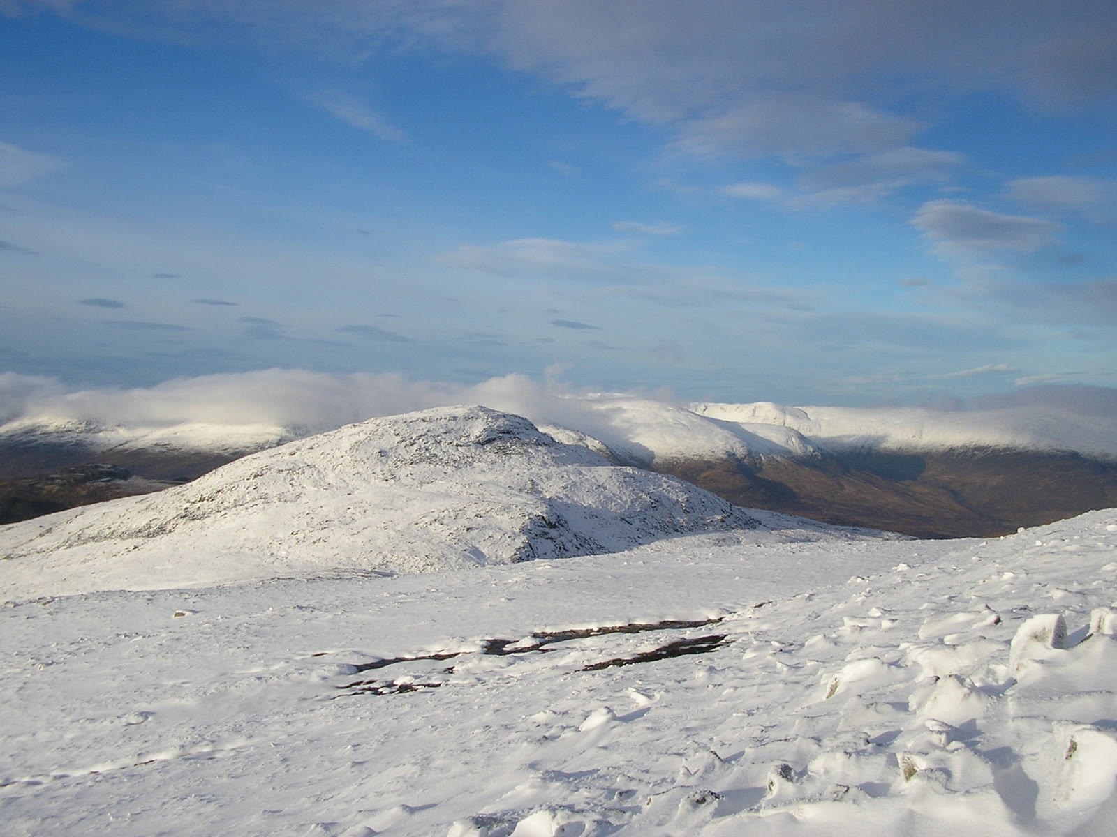 Creag Pitridh under snow in winter sun, cloud lying on the hills behind.