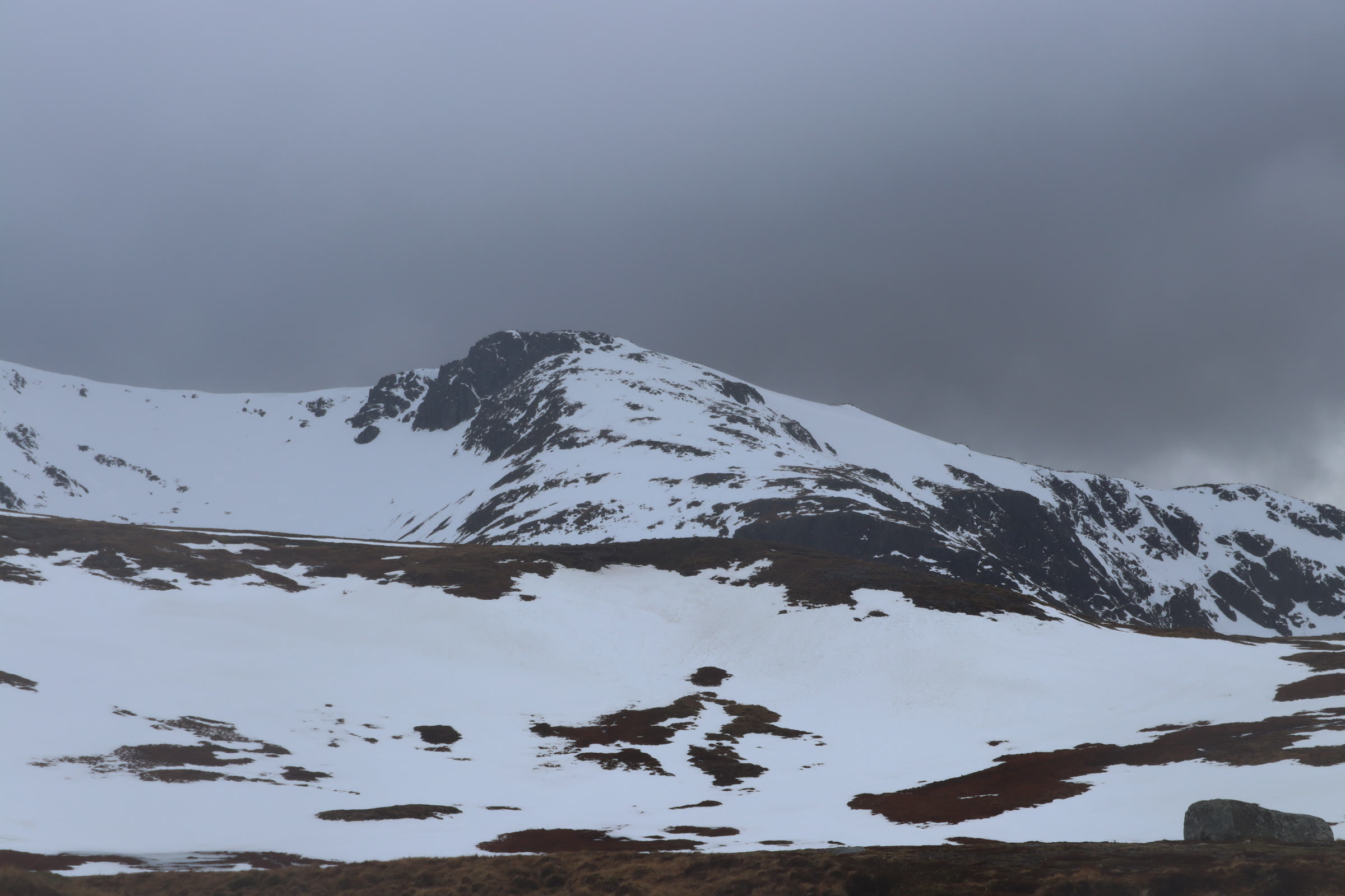 Creise under snow beneath a dark sky, its craggy top above a white corrie.
