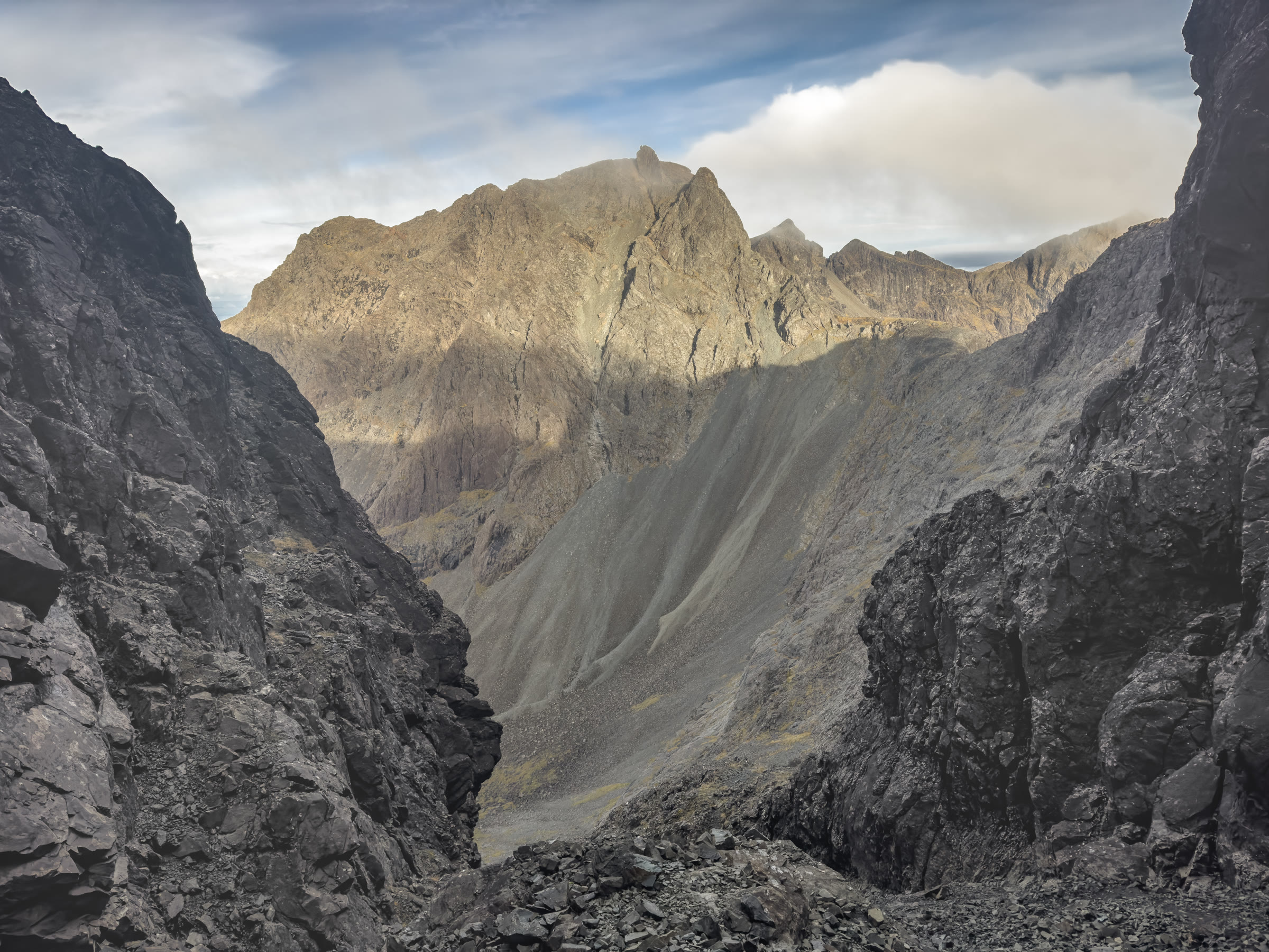 A sunlit Cuillin peak framed between dark rock walls near Sgùrr Alasdair.