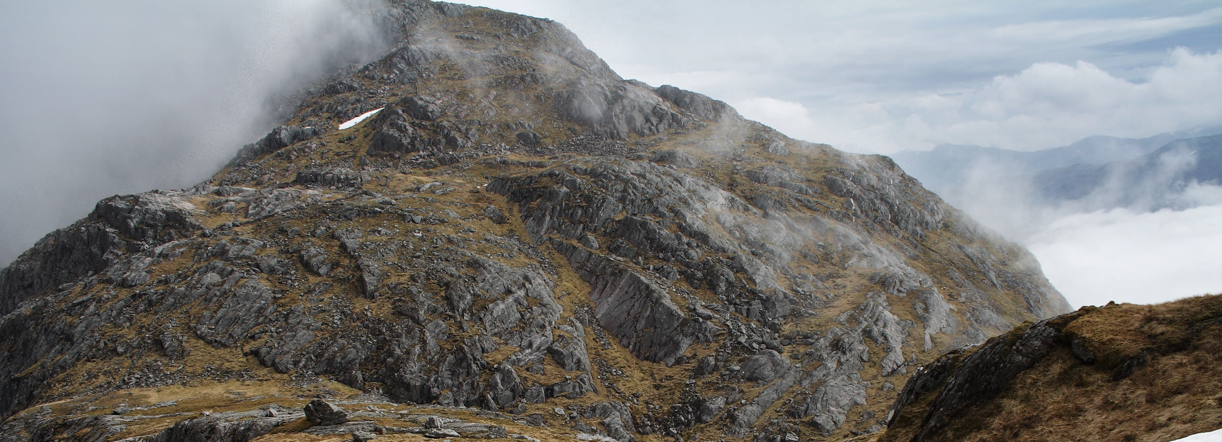 The rough, rocky peak of Garbh Chìoch Mhòr with cloud curling round it.