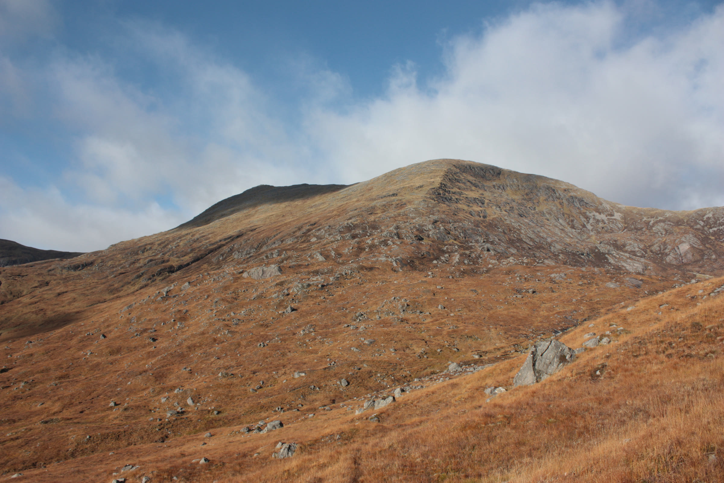 Gleouraich from a tawny hillside, bright cloud behind its top.