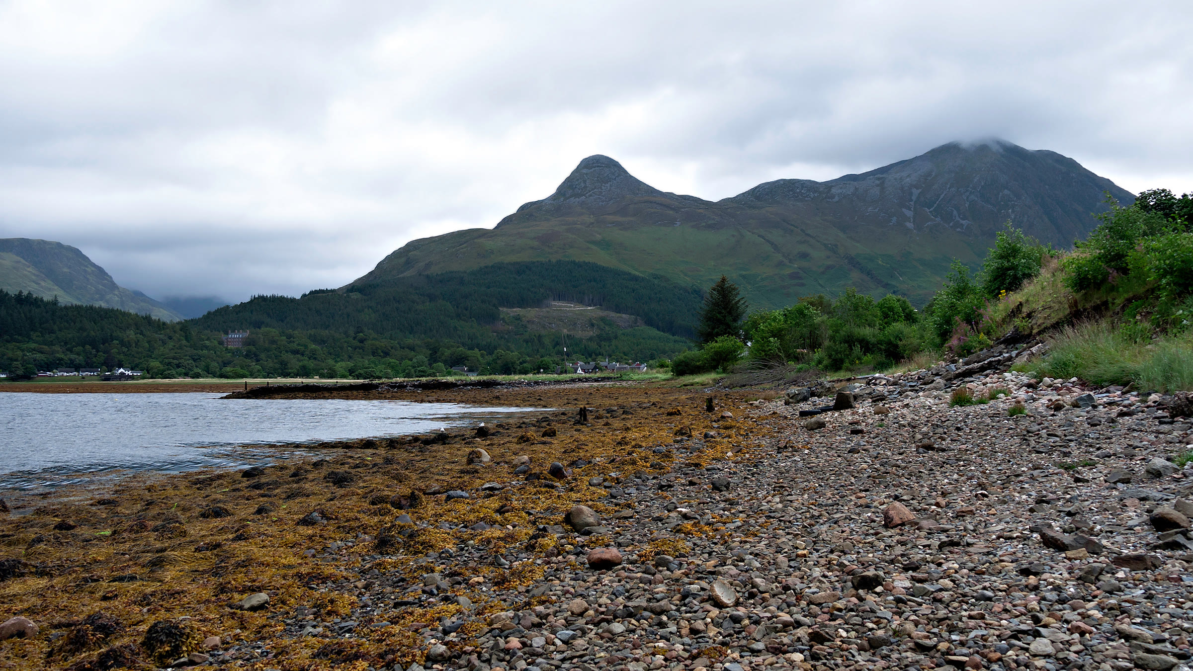 The shore of Loch Leven with the Pap of Glencoe and Sgòrr nam Fiannaidh above Glencoe village.