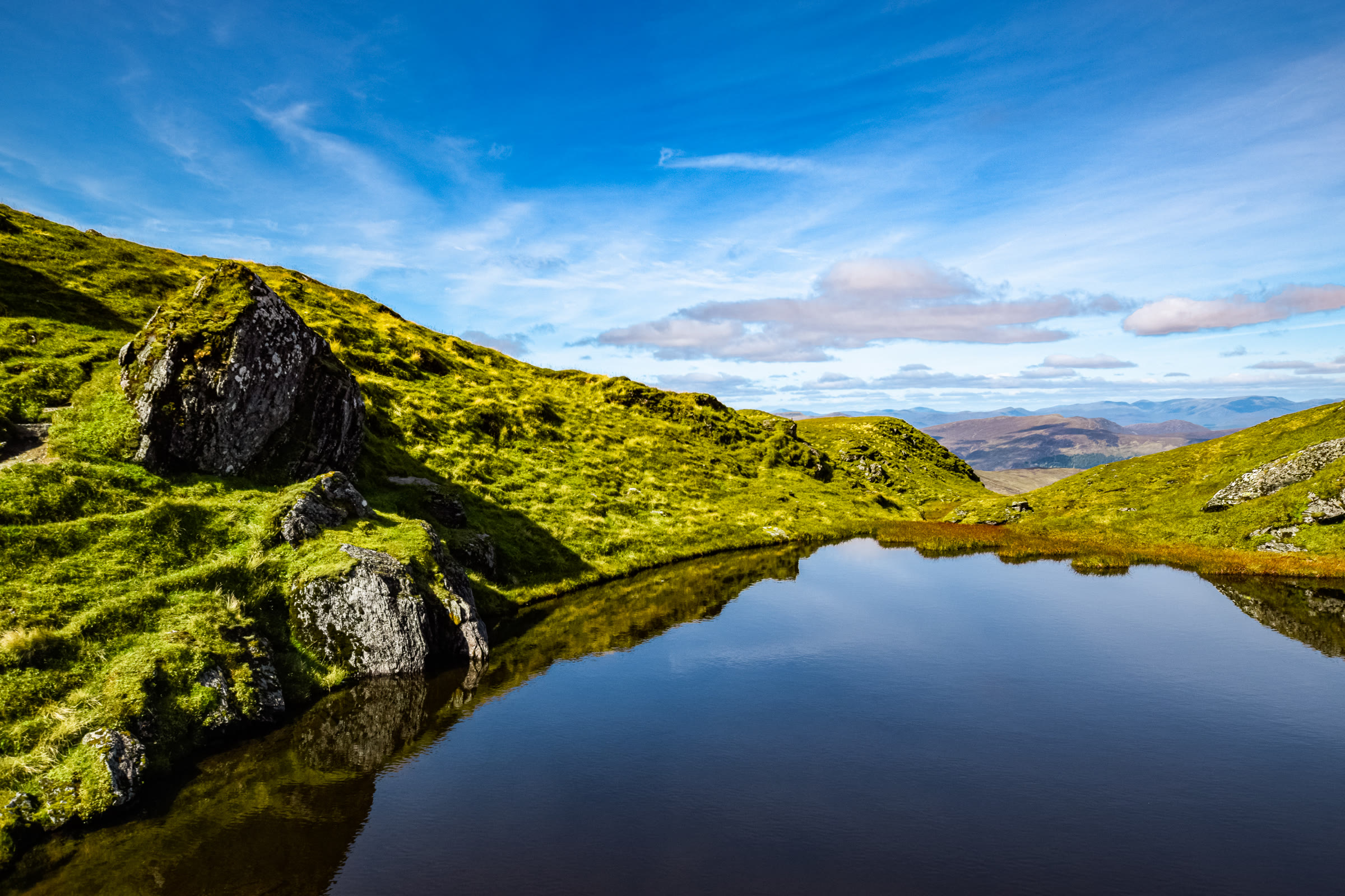 A small pool near the top of Meall nan Tarmachan reflecting a blue sky.