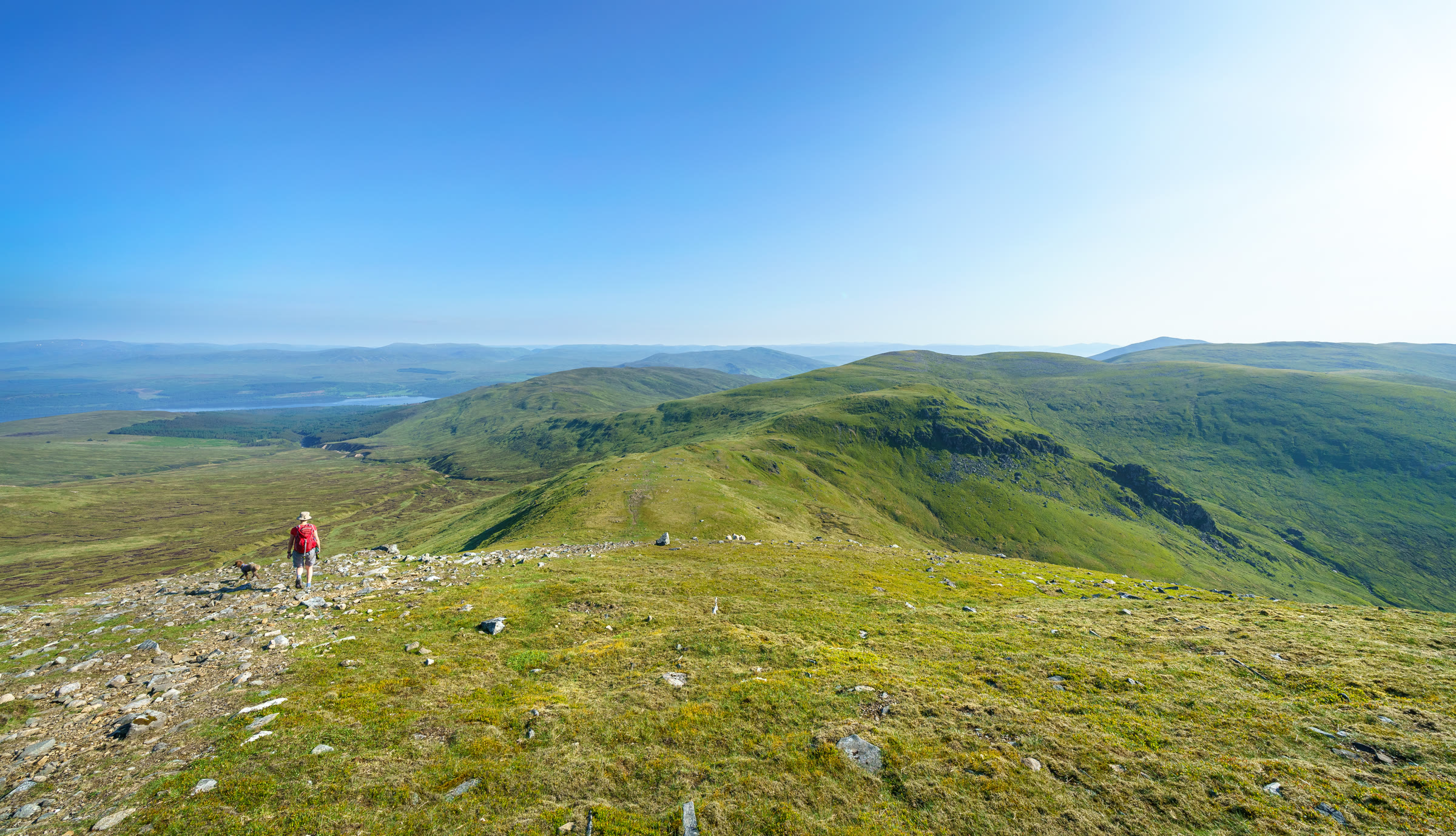 A walker on the broad grassy ridge from Càrn Gorm towards An Sgòrr and Meall Garbh.
