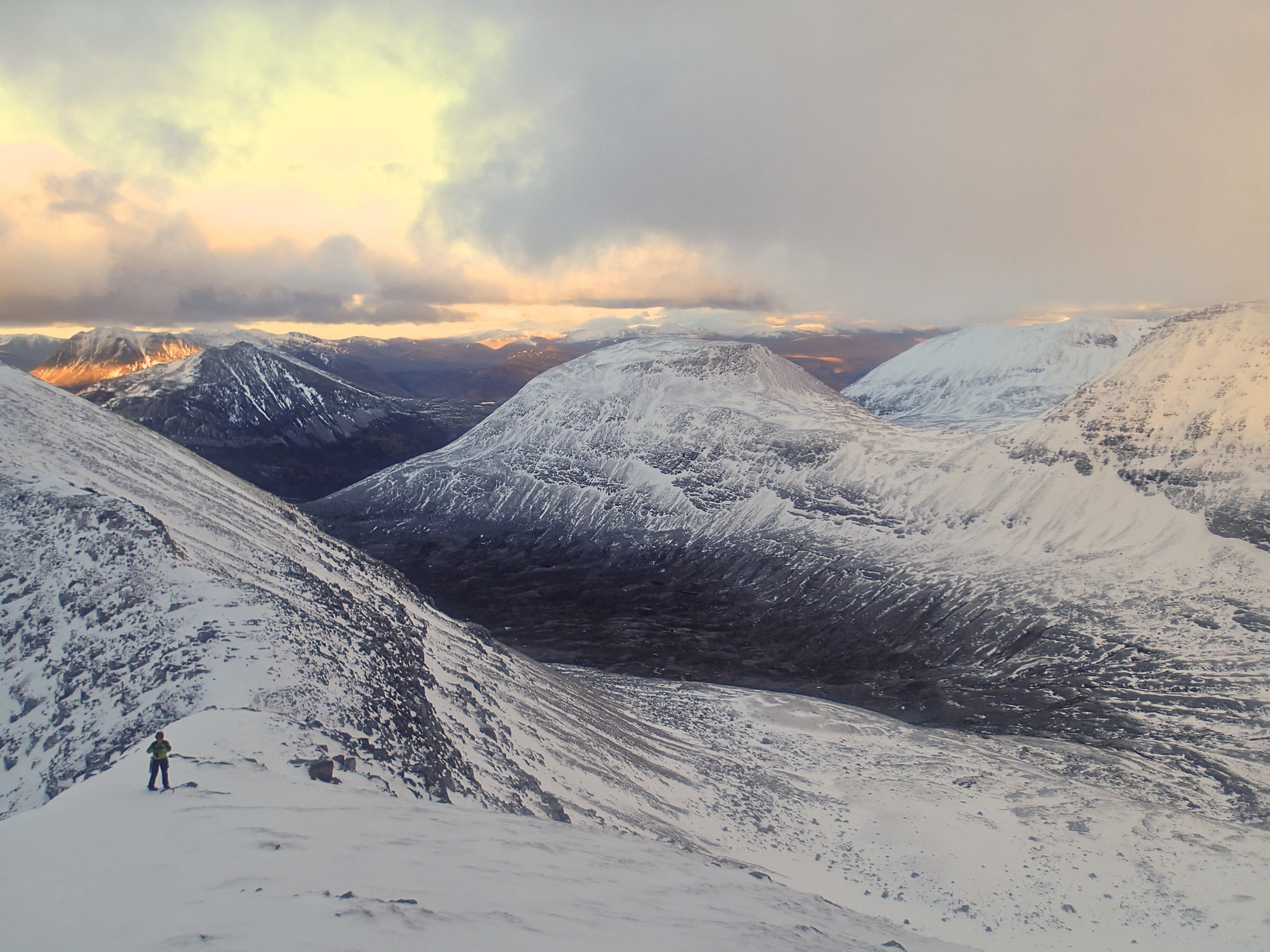 Ruadh Stac Mòr under snow at dusk, the last light on the hills behind.