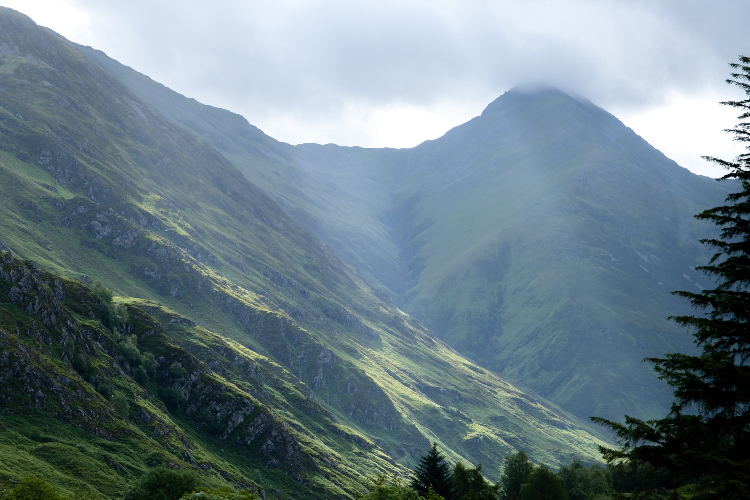 Sgùrr Fhuaran in morning sun, its top touched by cloud above a steep green glen.