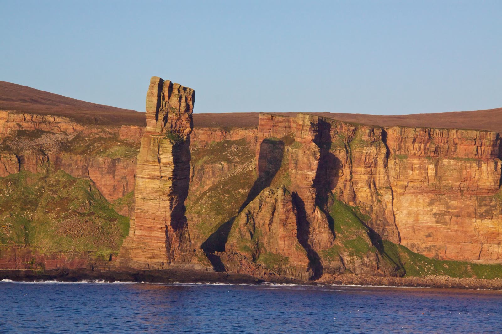 The Old Man of Hoy and the red cliffs of Hoy seen from the sea in evening light.