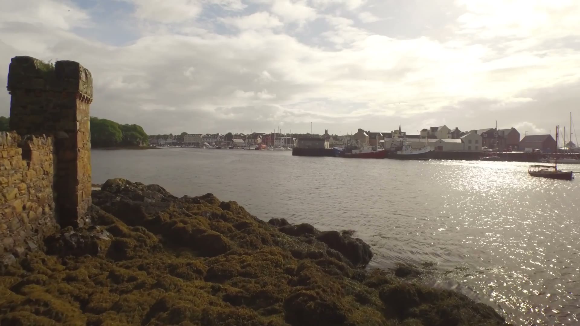 Stornoway harbour across the water from the Lews Castle shore, sun breaking through cloud.