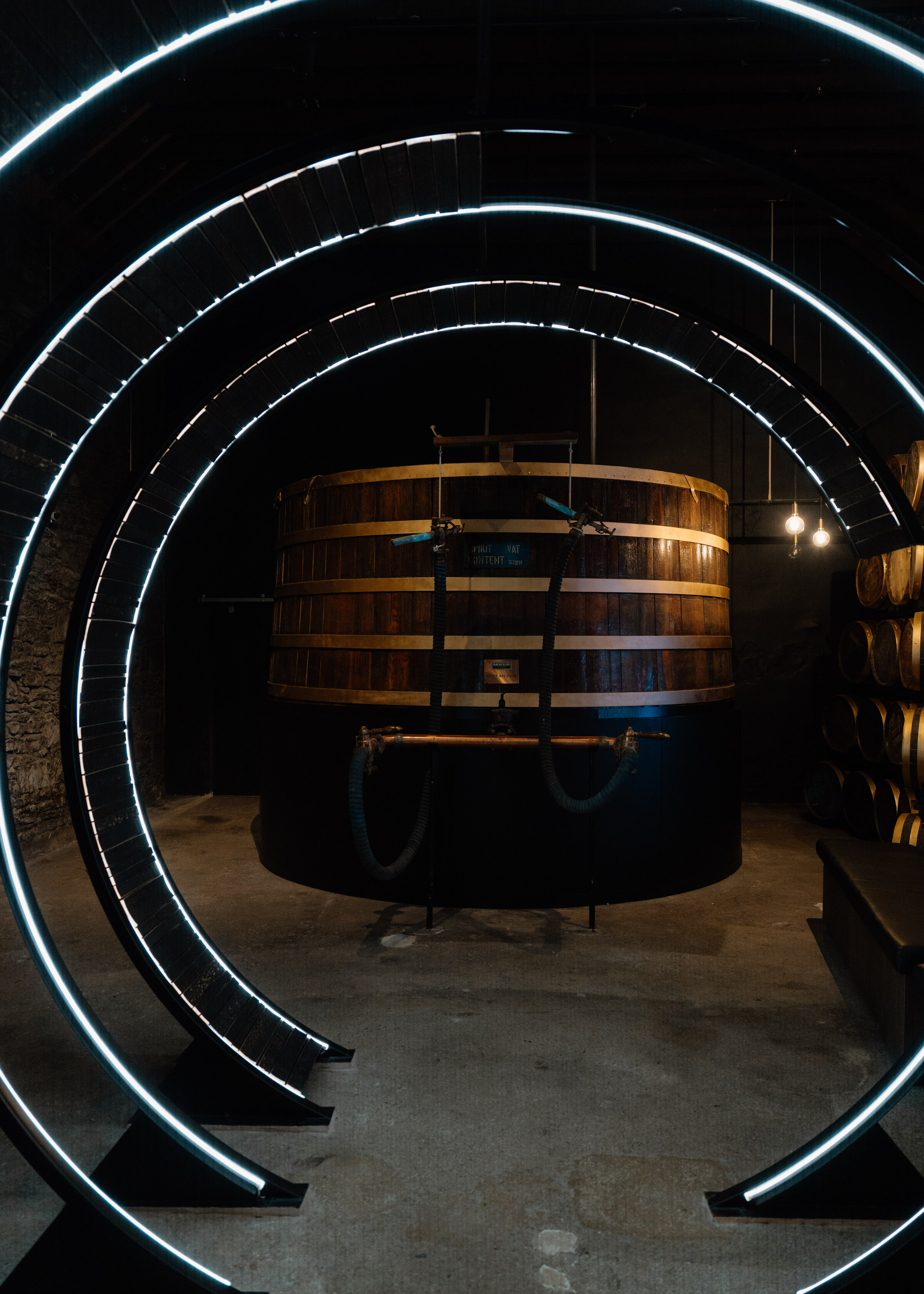 A wooden washback standing in a dark room, framed by rings of white light.