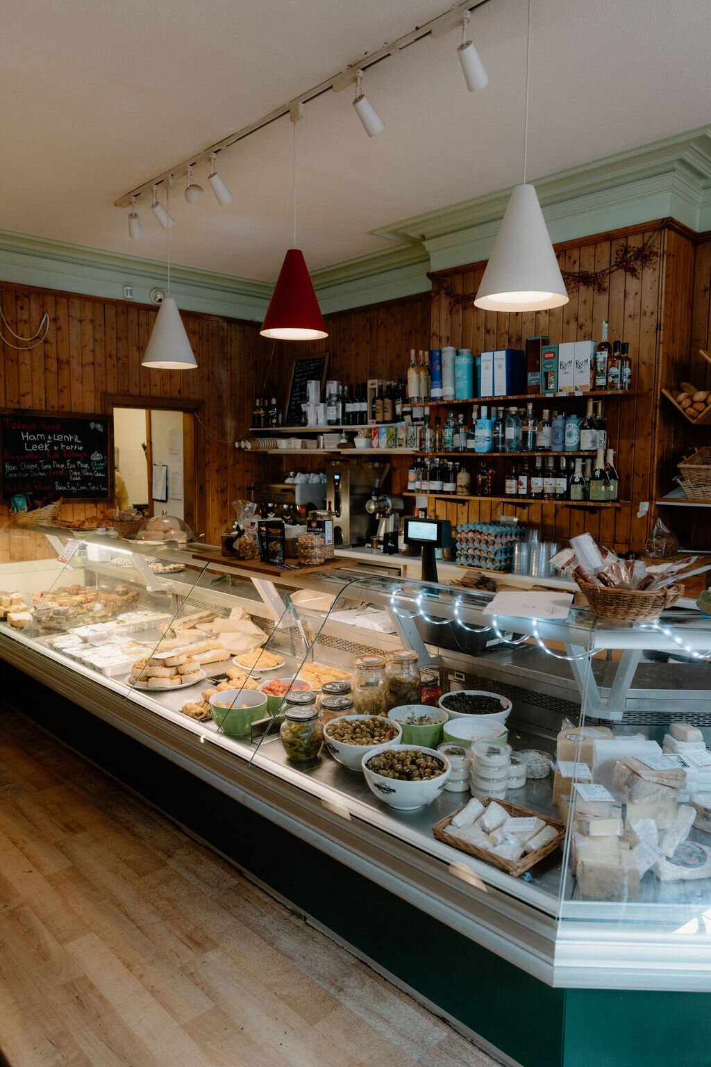 Jars, tinned goods and baked treats crowd a wood-panelled shop's counter and shelving.