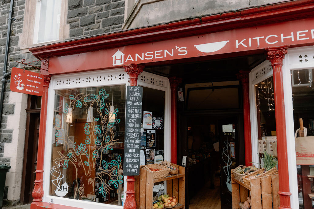 Painted vines twist across Hansen's Kitchen shopfront beside baskets of produce.