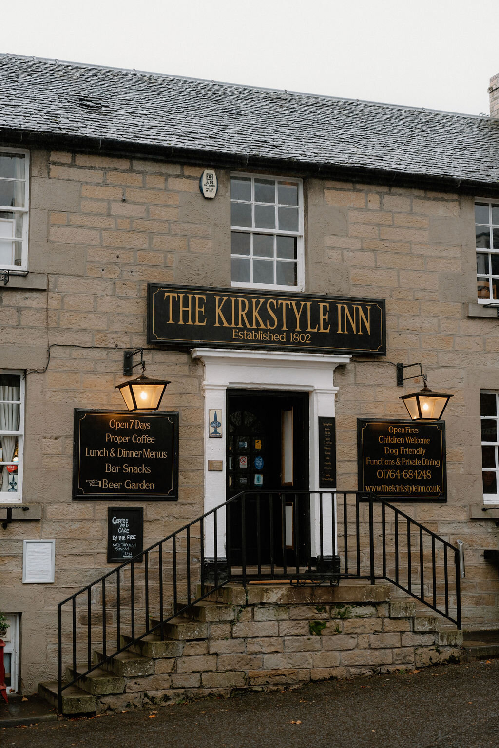 The Kirkstyle Inn's own sign, established 1802, hangs above its entrance and lit lanterns.