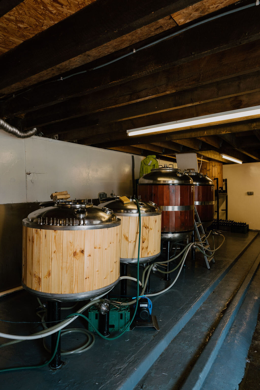 Wooden-clad brewing vessels with copper fittings stand beneath a timber-beamed roof at Moulin Brewery.