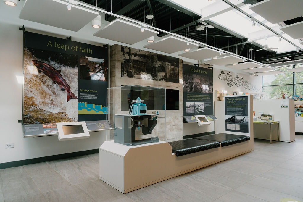 A salmon-leap exhibit with an illustrated banner reading 'A leap of faith' sits in a visitor centre display.