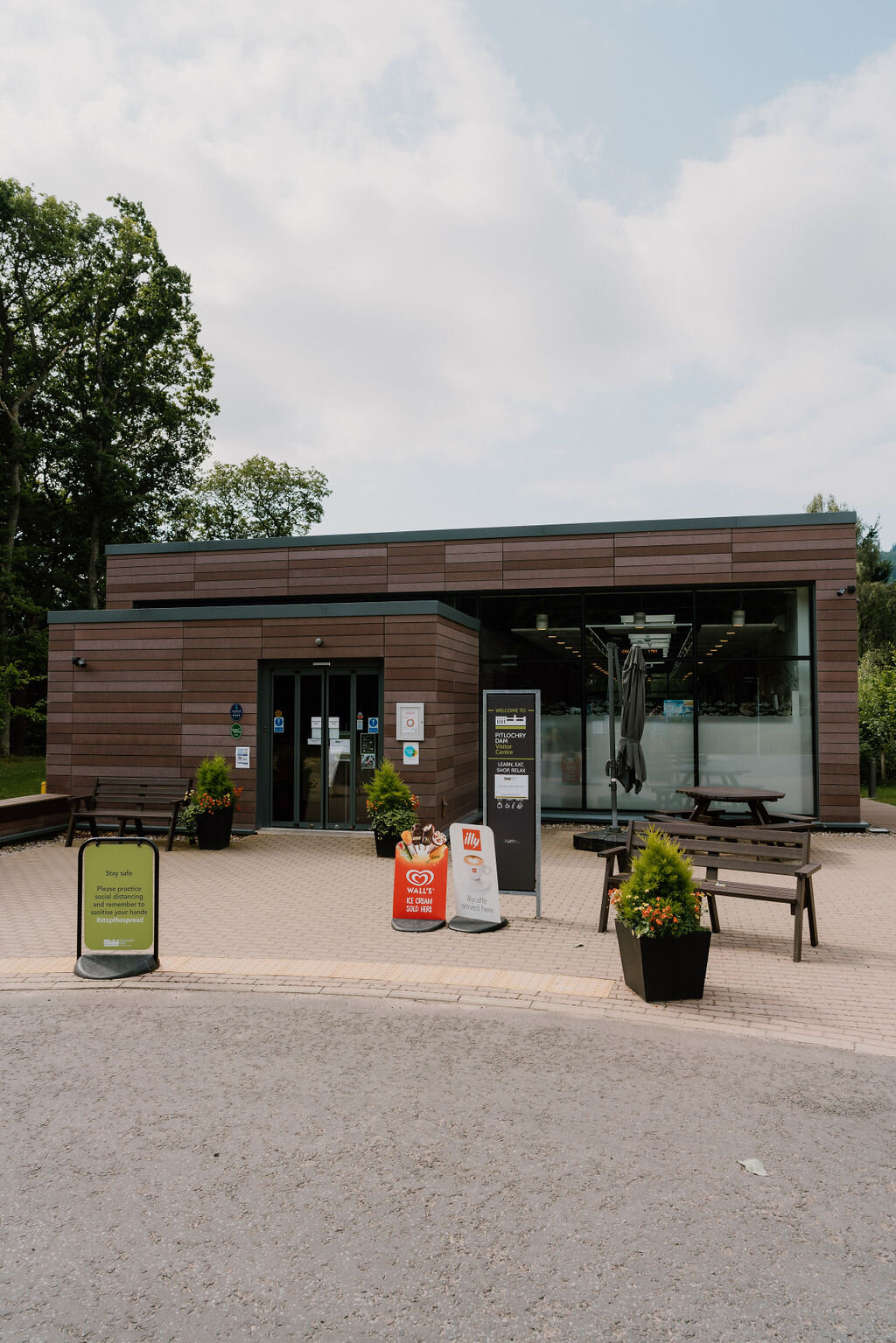 The Pitlochry Dam visitor centre's timber-clad entrance has benches and planters outside.