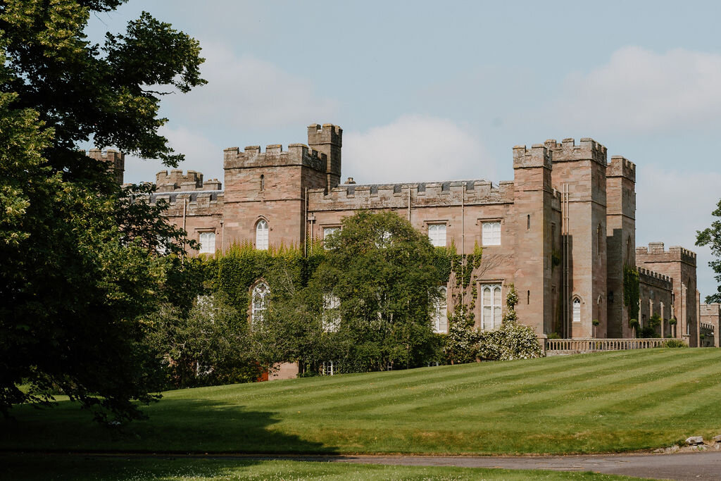 Scone Palace's red sandstone castellated facade rises beyond a wide lawn.