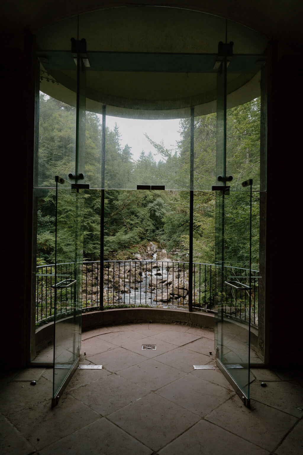 Open glass doors at Ossian's Hall look out over a rushing river gorge at The Hermitage, Dunkeld.
