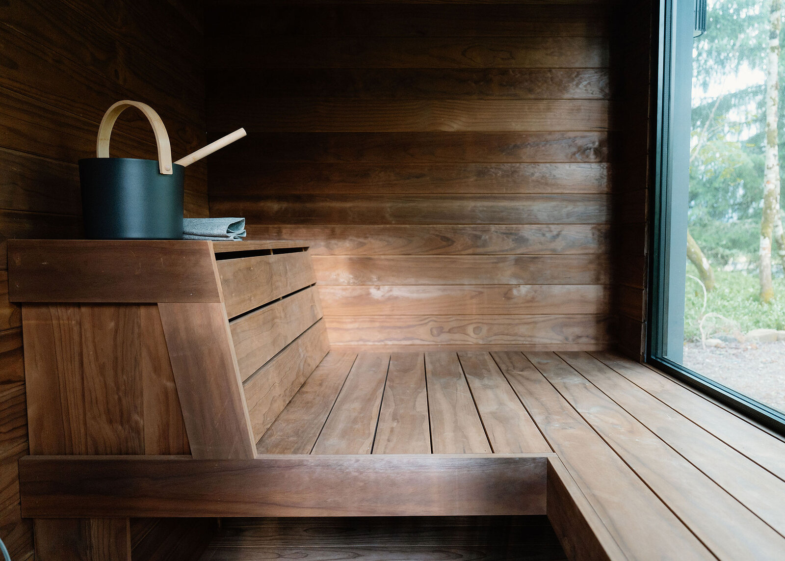 A landscape view of the sauna benches running to a floor-to-ceiling window onto the birches.