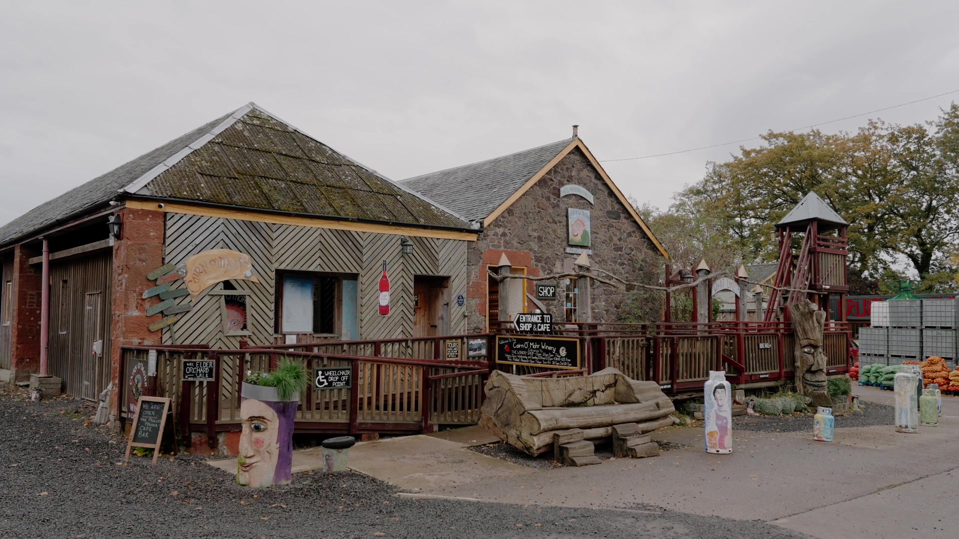 Cairn O' Mhor's timber-clad shop and café buildings, hand-painted signs and carved wooden totems along the entrance ramp.
