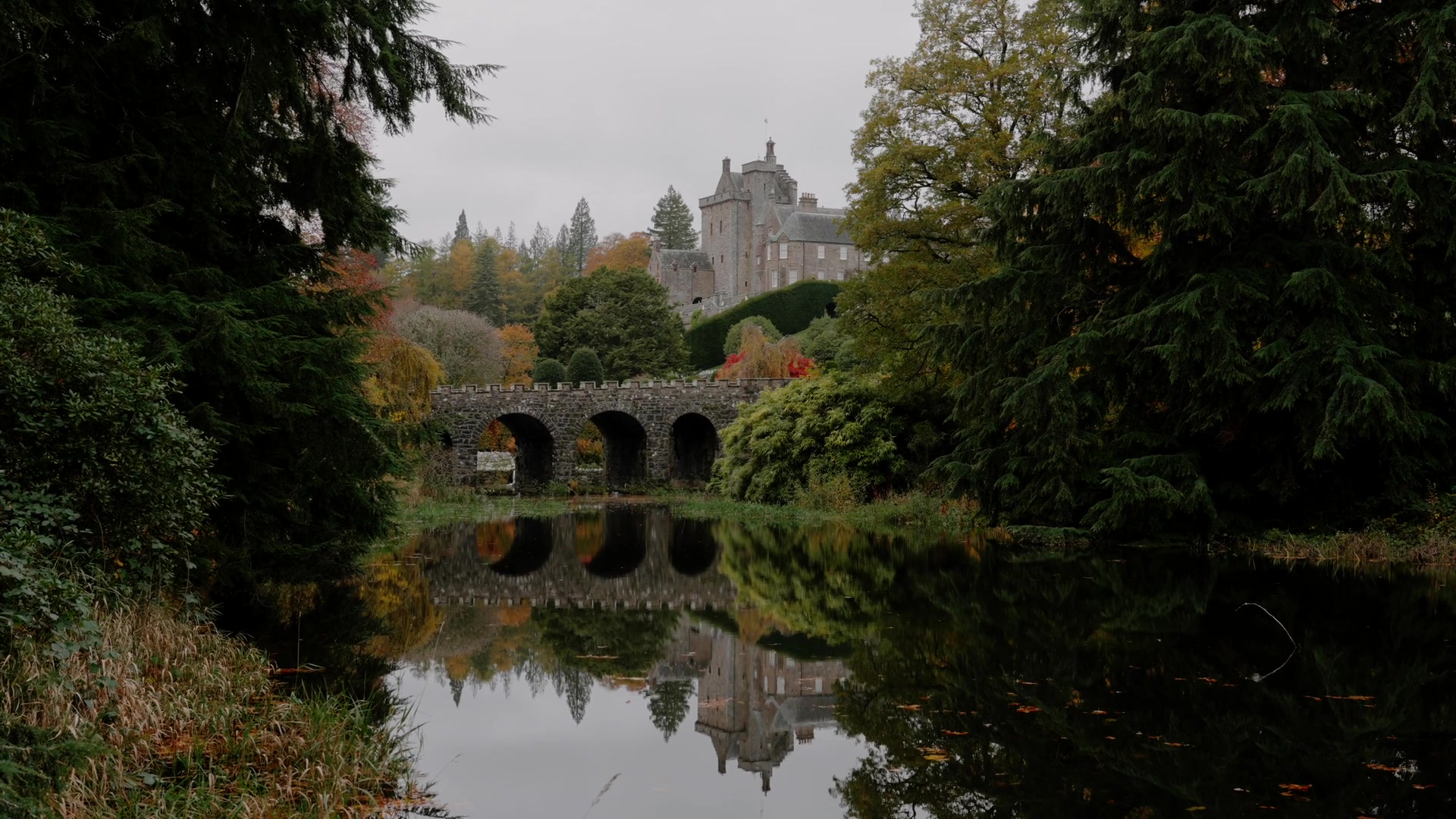 The same formal garden seen from a different angle, its hedged parterres, statues and autumn-coloured trees spread across the grounds.