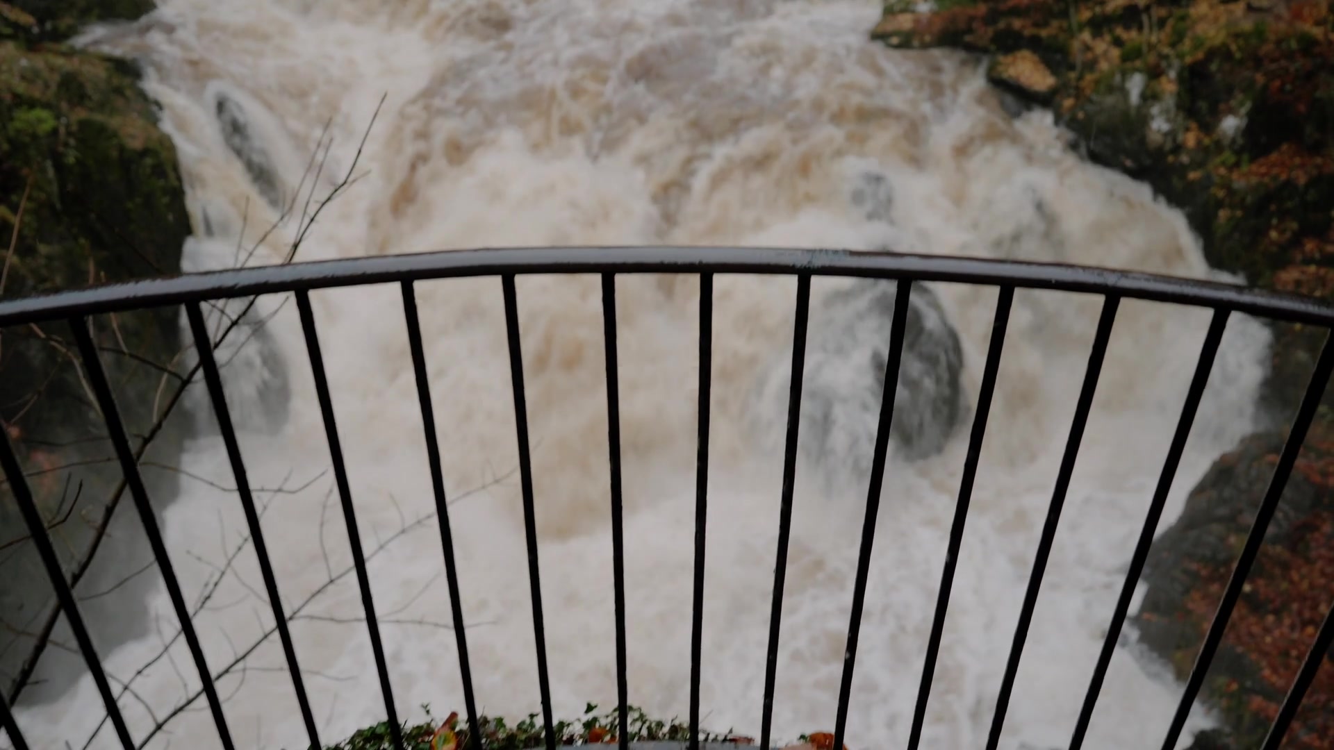 the flooded Black Linn Falls seen through a viewing railing, spray rising off the rocks
