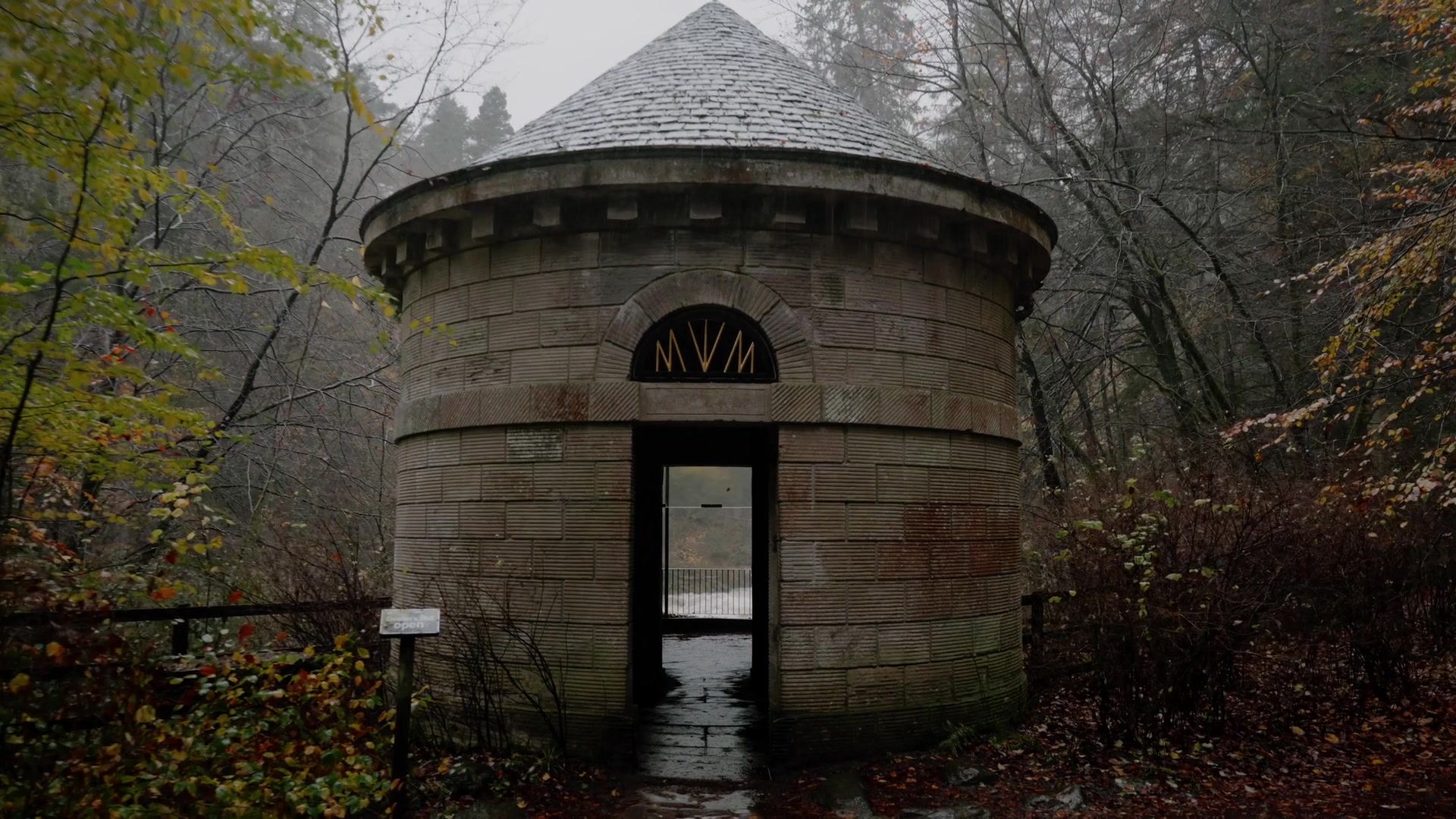 the Black Linn Falls in full flood seen through Ossian's Hall's glass doors, mist rising off the trees beyond