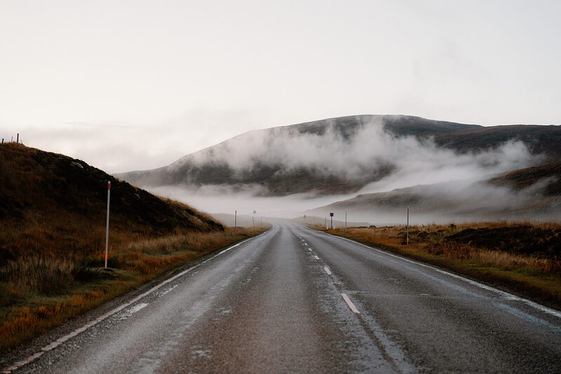 A single-track road runs straight toward mist-covered hills in Ross and Cromarty.