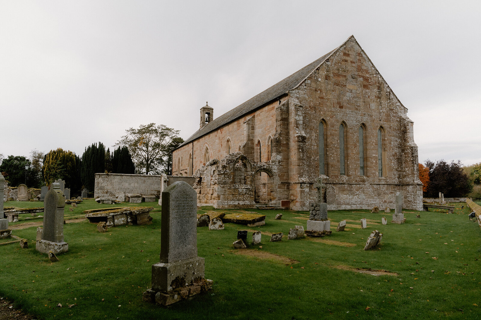 A ruined medieval church stands among gravestones in a Ross and Cromarty churchyard.