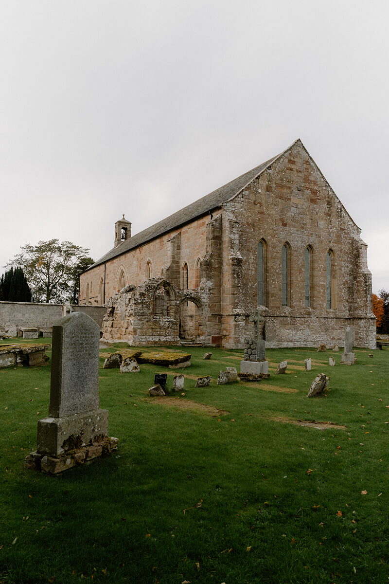 A sandstone church with a bellcote and pointed windows stands in a Ross and Cromarty graveyard.