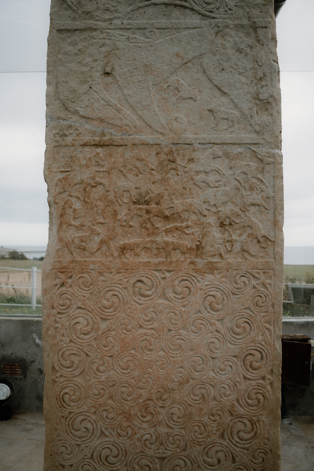 Carved figures and interlace patterns cover a weathered Pictish stone in close detail in Ross and Cromarty.