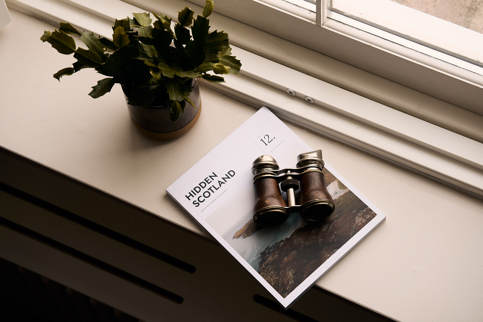 Issue 12 on a windowsill under a pair of old binoculars