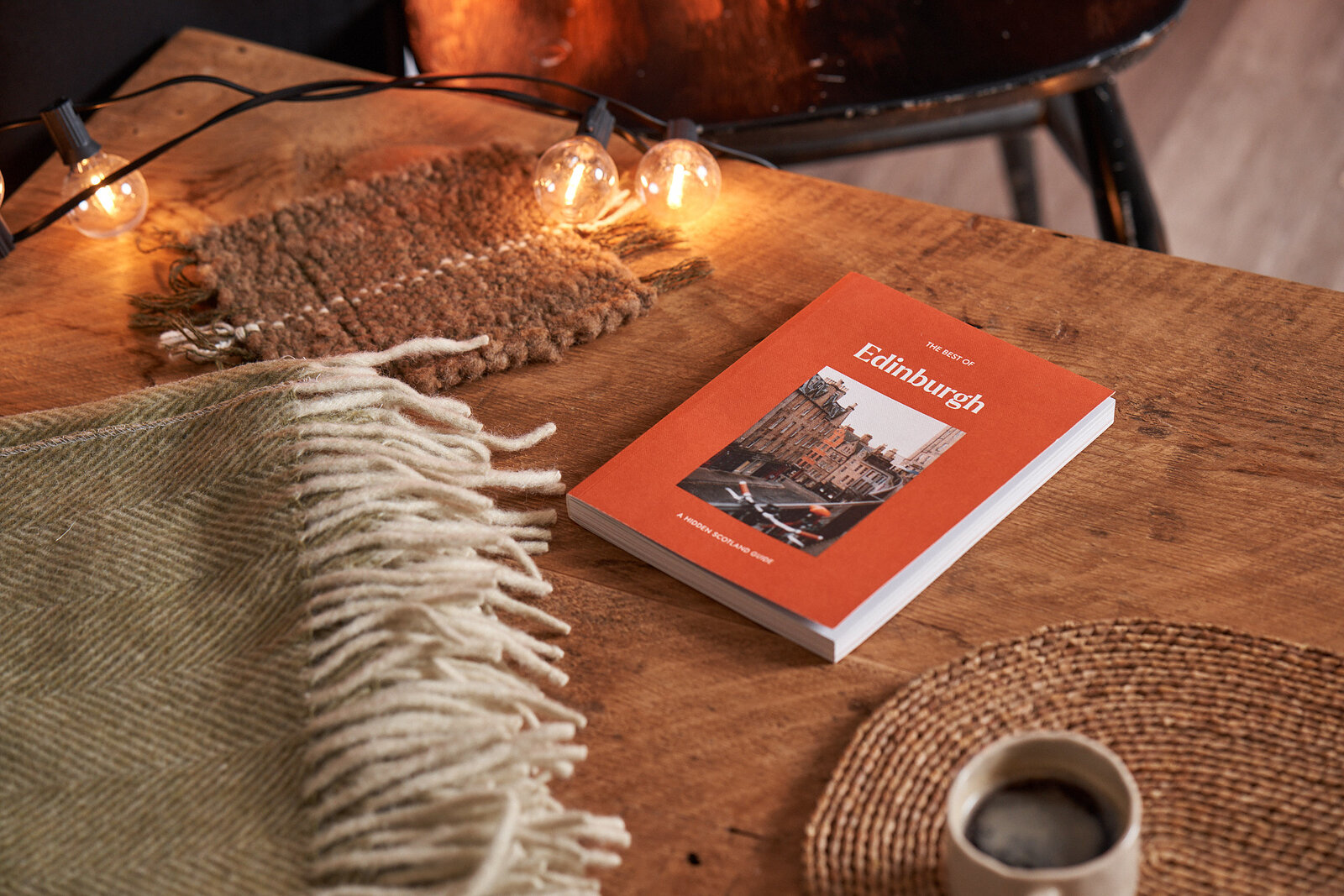 The Best of Edinburgh on a wooden table beside a mug